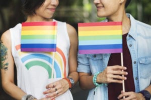 Two women holding LGBT rainbow flags