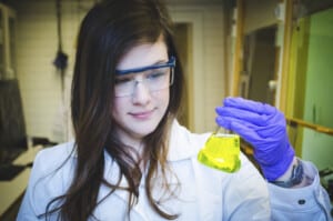 Female chemist holding a beaker with a yellow fluid